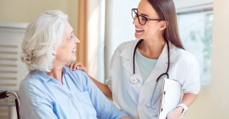 sonriente paciente vieja y enfermera en el sistema sanitario noruego